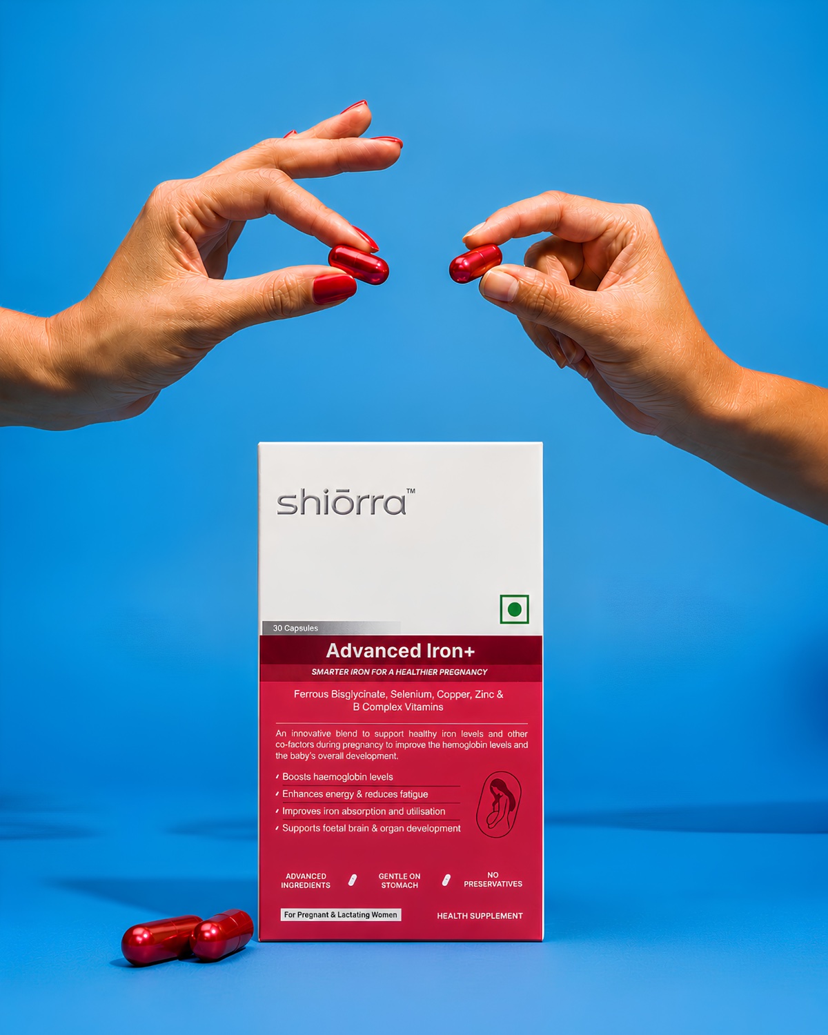 Two hands offering Shiōrra Advanced Iron+ capsules beside the pack and fresh ginger on a blue backdrop